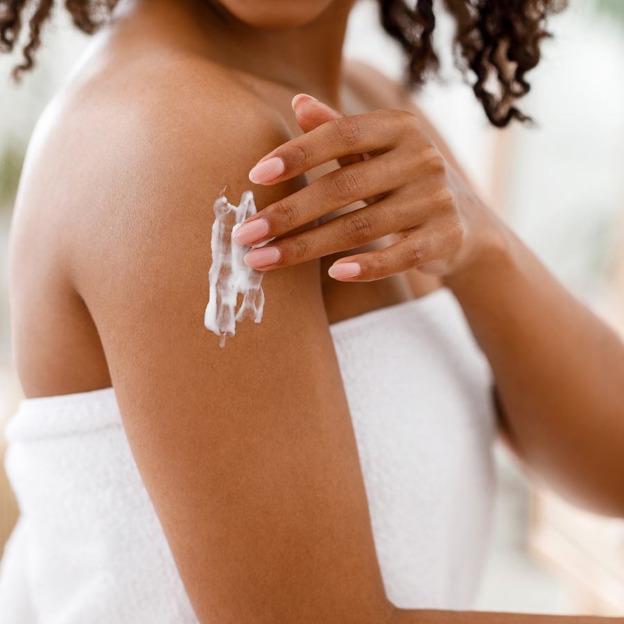 dark skinned woman applying lotion
