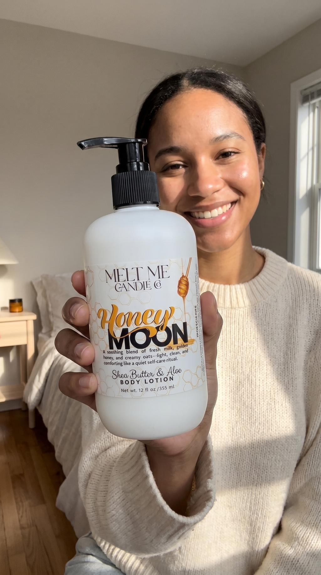 Person holding a bottle of 'Honey Moon' shea butter and aloe lotion in a home setting.