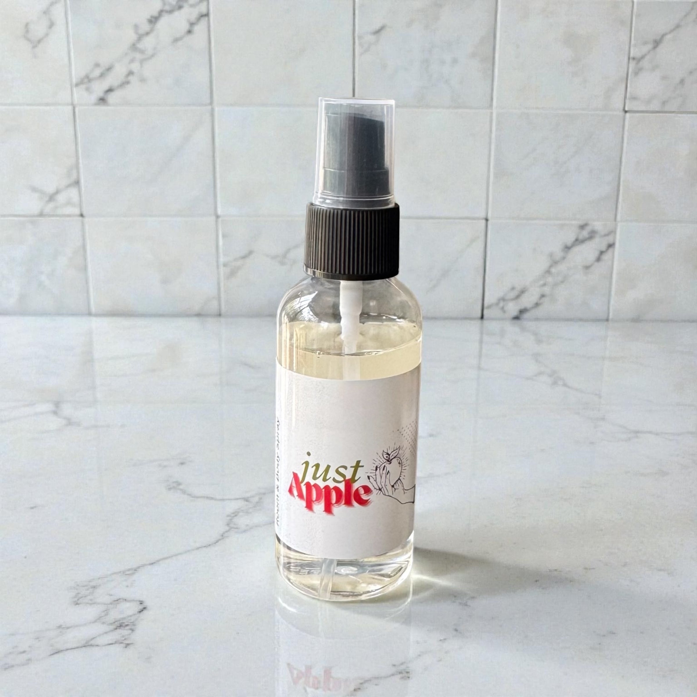 Clear spray bottle with black nozzle on a marble surface