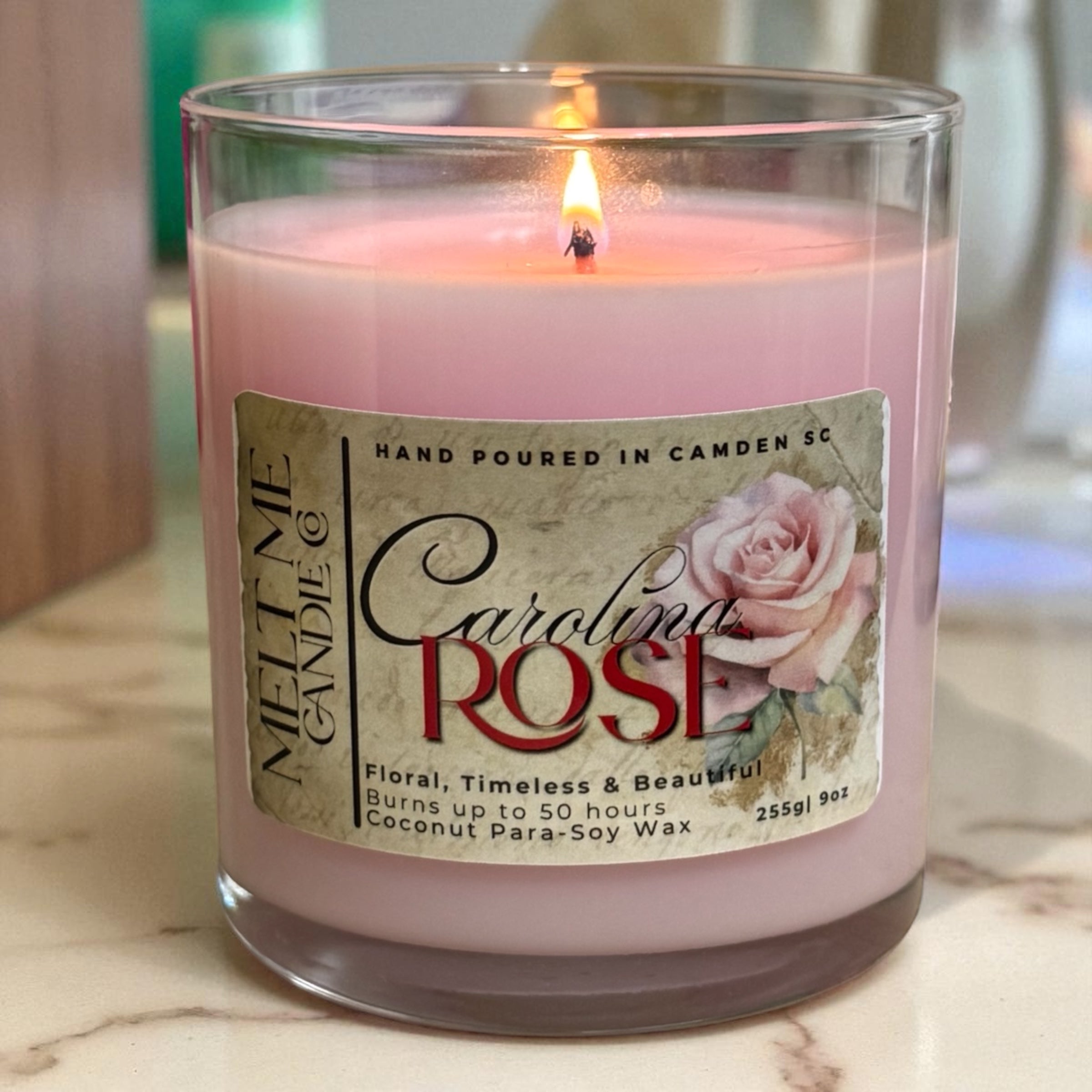 Pink candle labeled 'Carolina Rose' with a rose design on a marble surface.