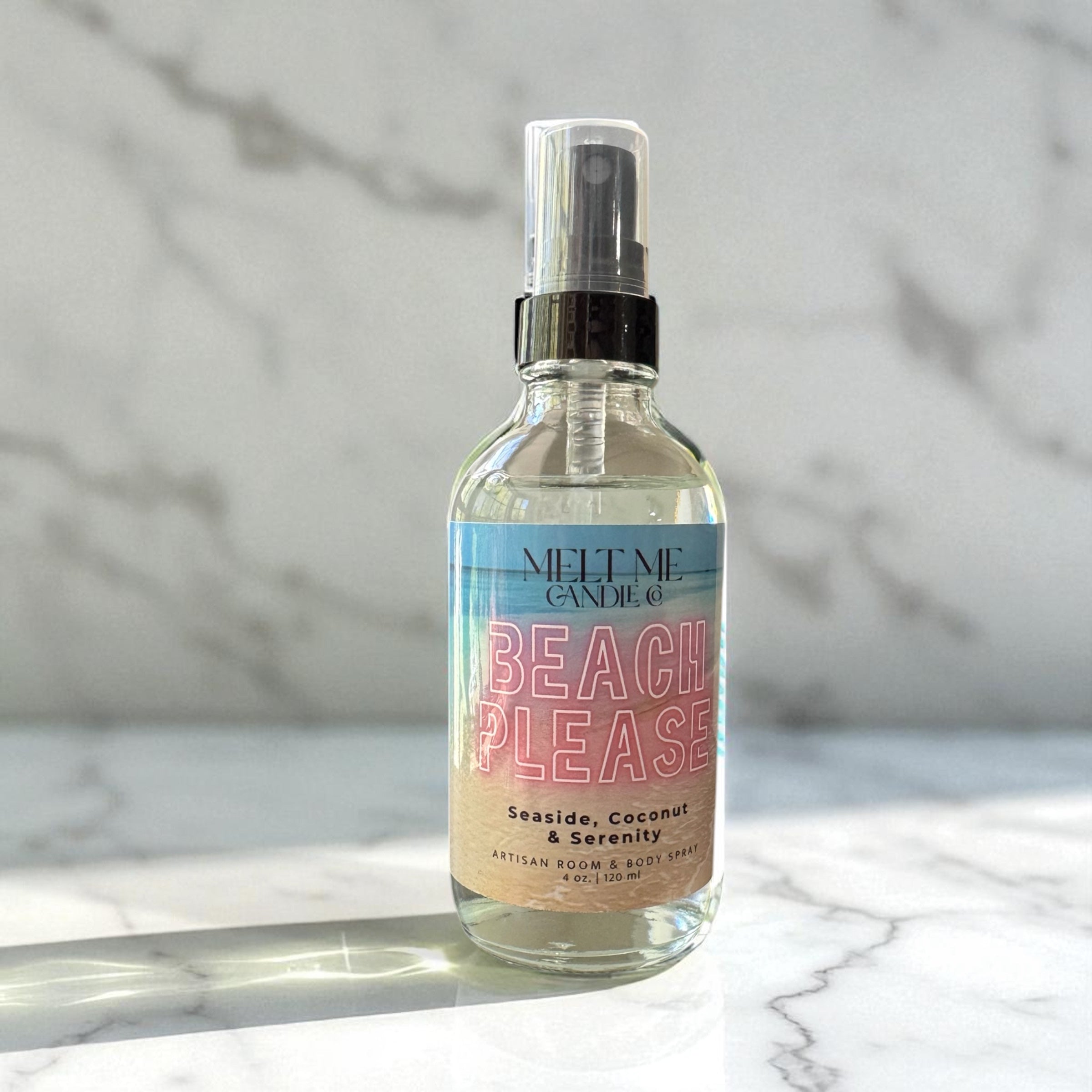 Spray bottle labeled 'Beach Please' on a marble surface with a light gray background
