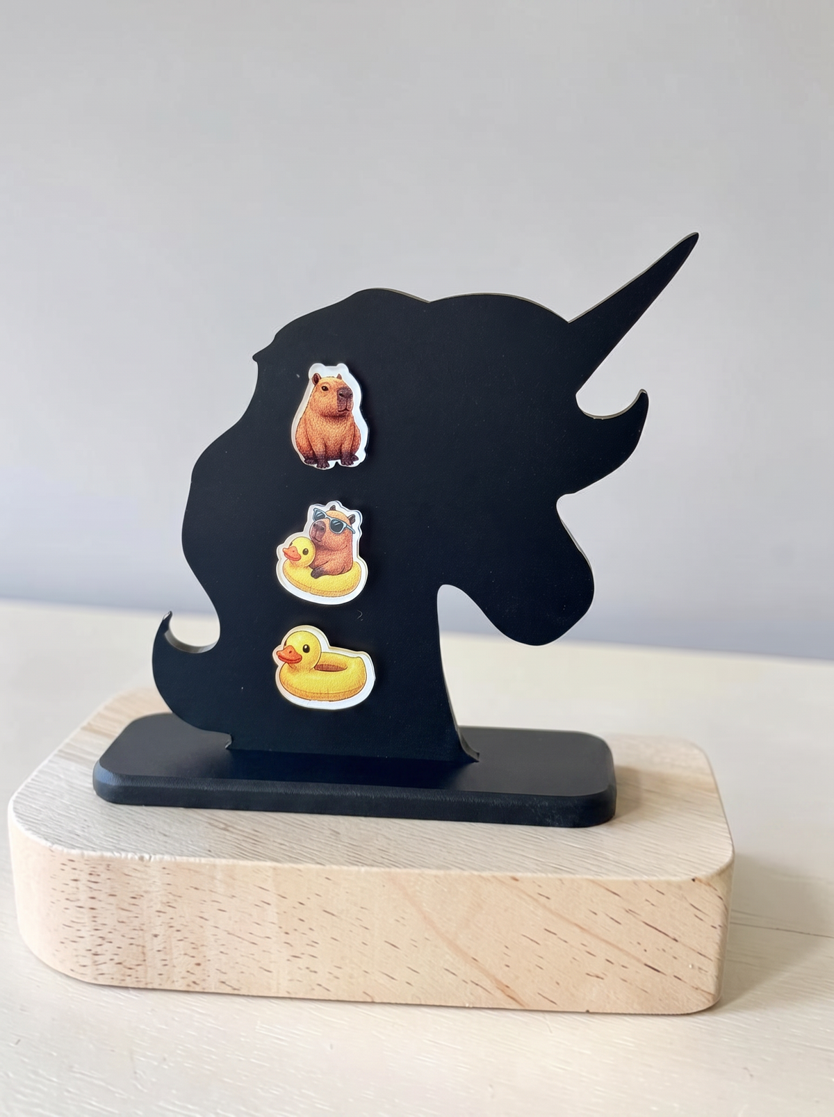 3 earring set of capybara earrings, set on a black acrylic earring holder.