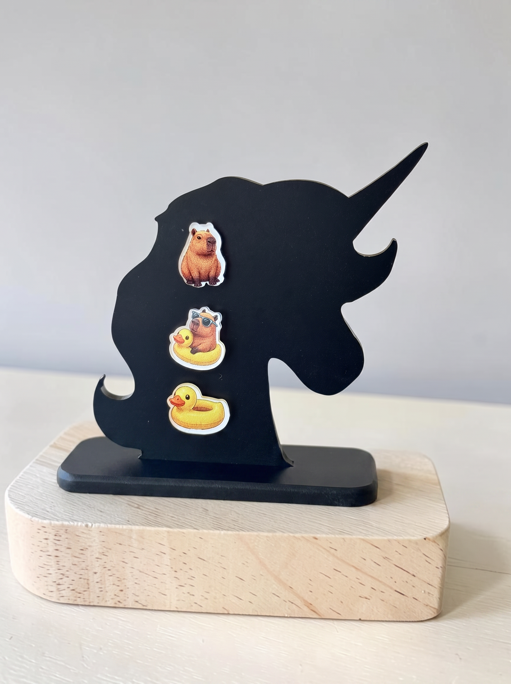 3 earring set of capybara earrings, set on a black acrylic earring holder. 