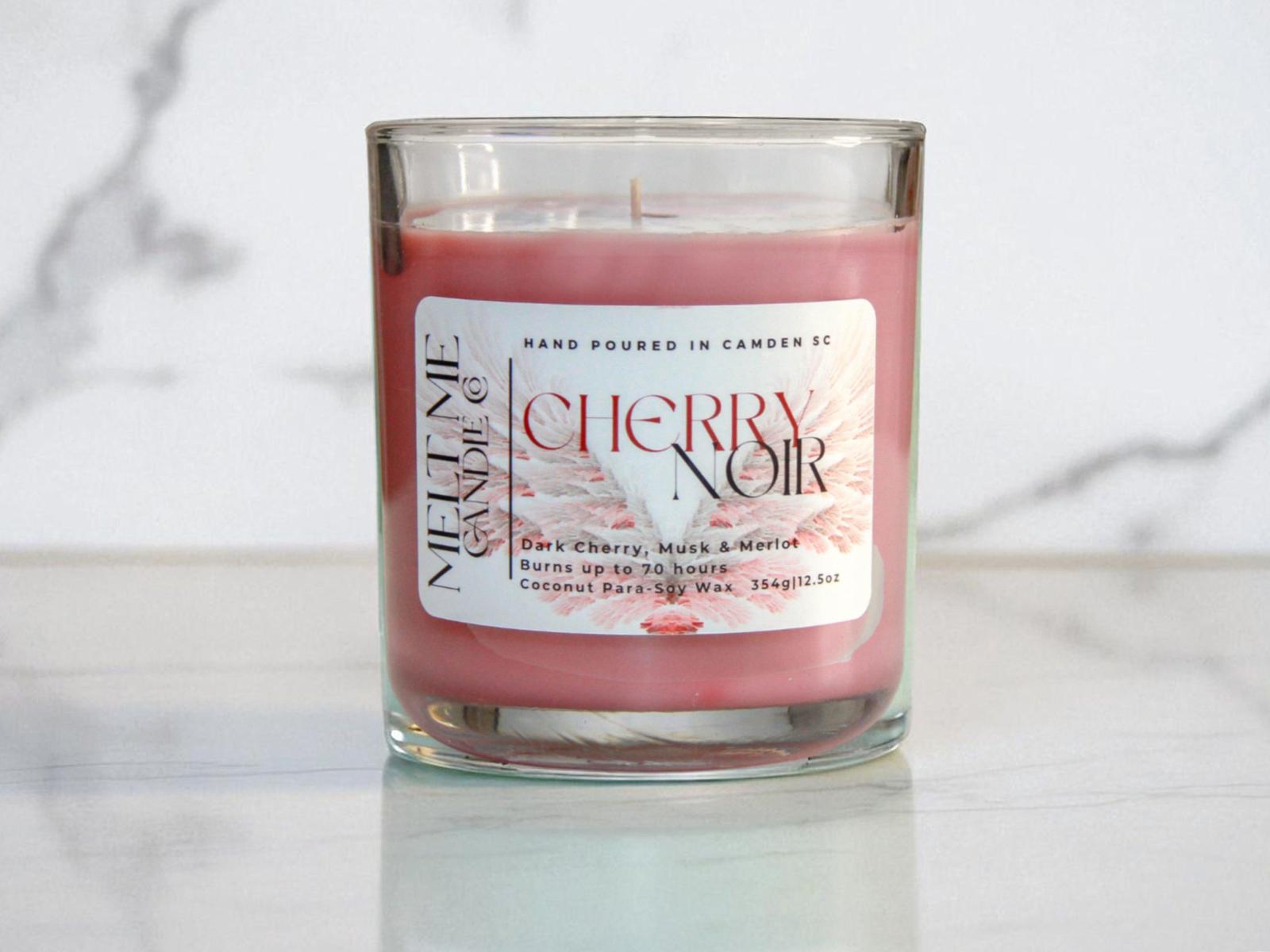 Candle in a glass jar with a 'Cherry Noir' label on a light background