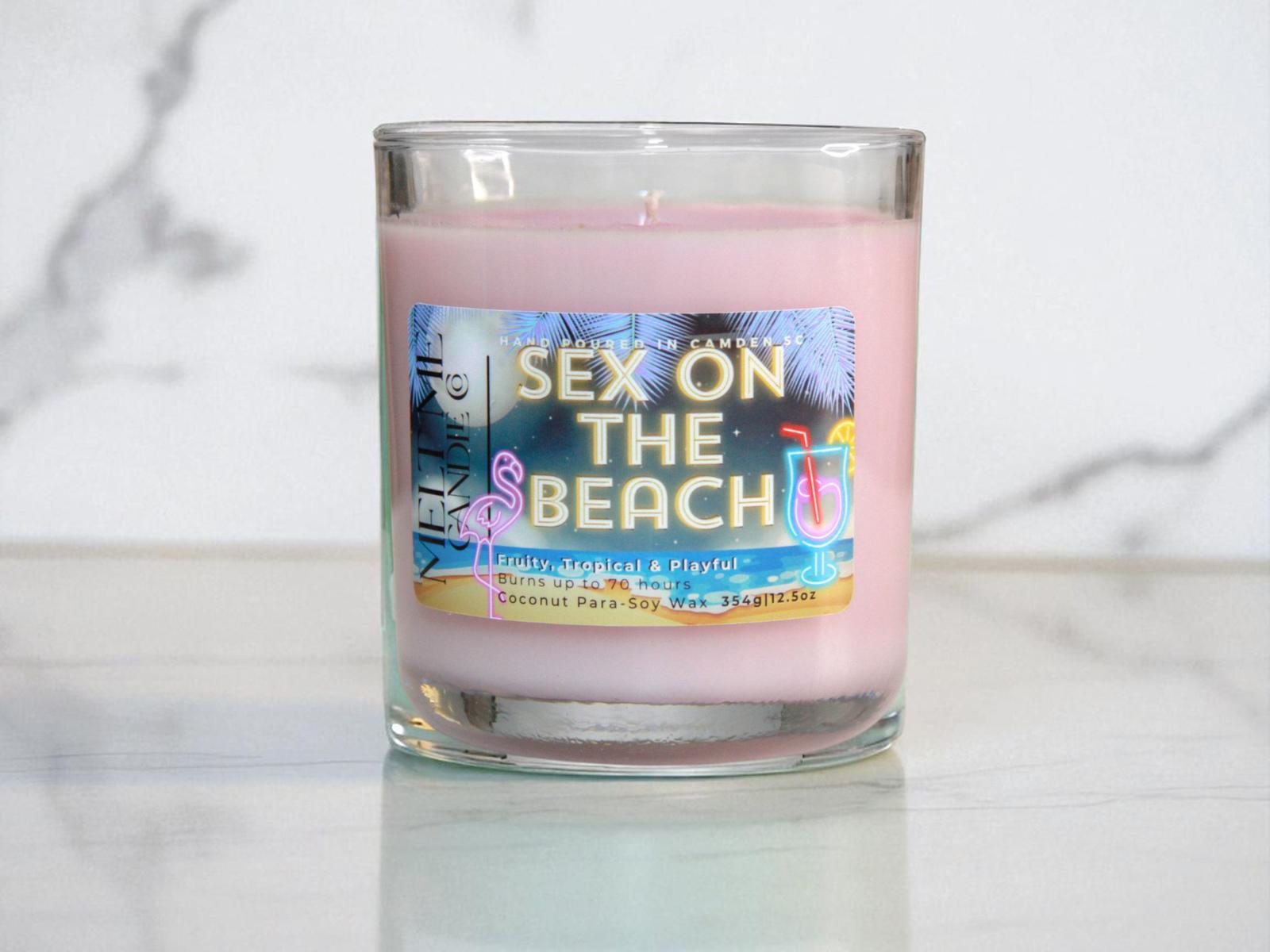 Pink candle with a colorful 'Sex on the Beach' label on a white marble surface