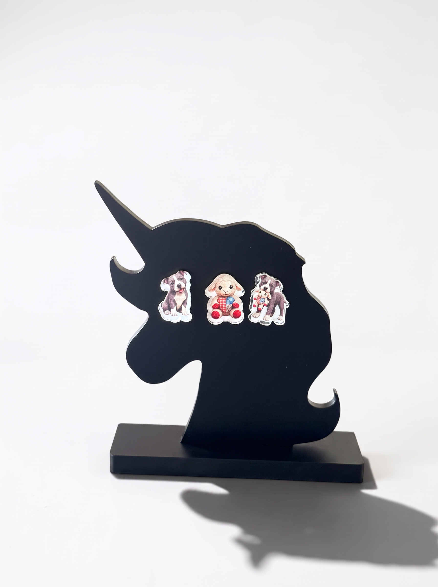 Three small pitt bull themed acrylic earrings displayed on a black unicorn-shaped stand against a white background