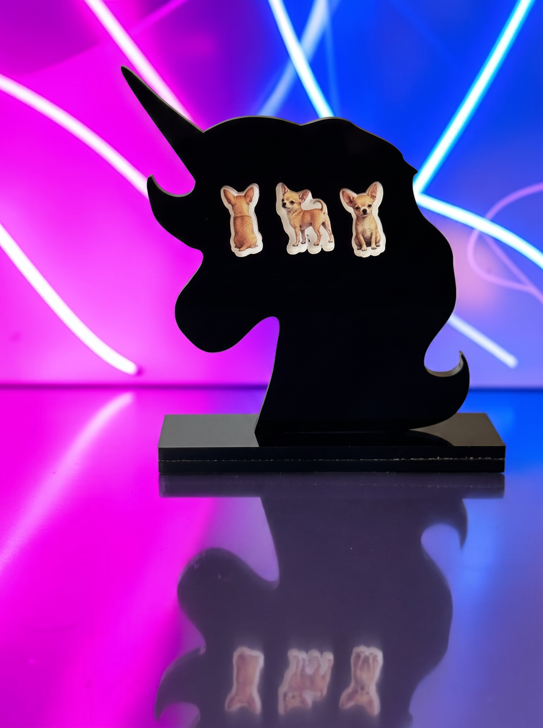Three small dog-shaped earrings displayed on a black unicorn-shaped stand against a neon pink and blue background.