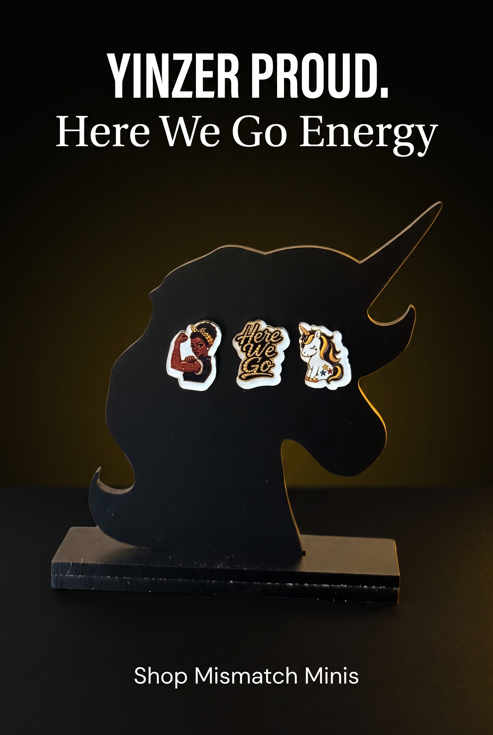 A black unicorn-shaped display stand holding three black-and-yellow acrylic stud earrings against a black promotional background with a warm yellow glow.